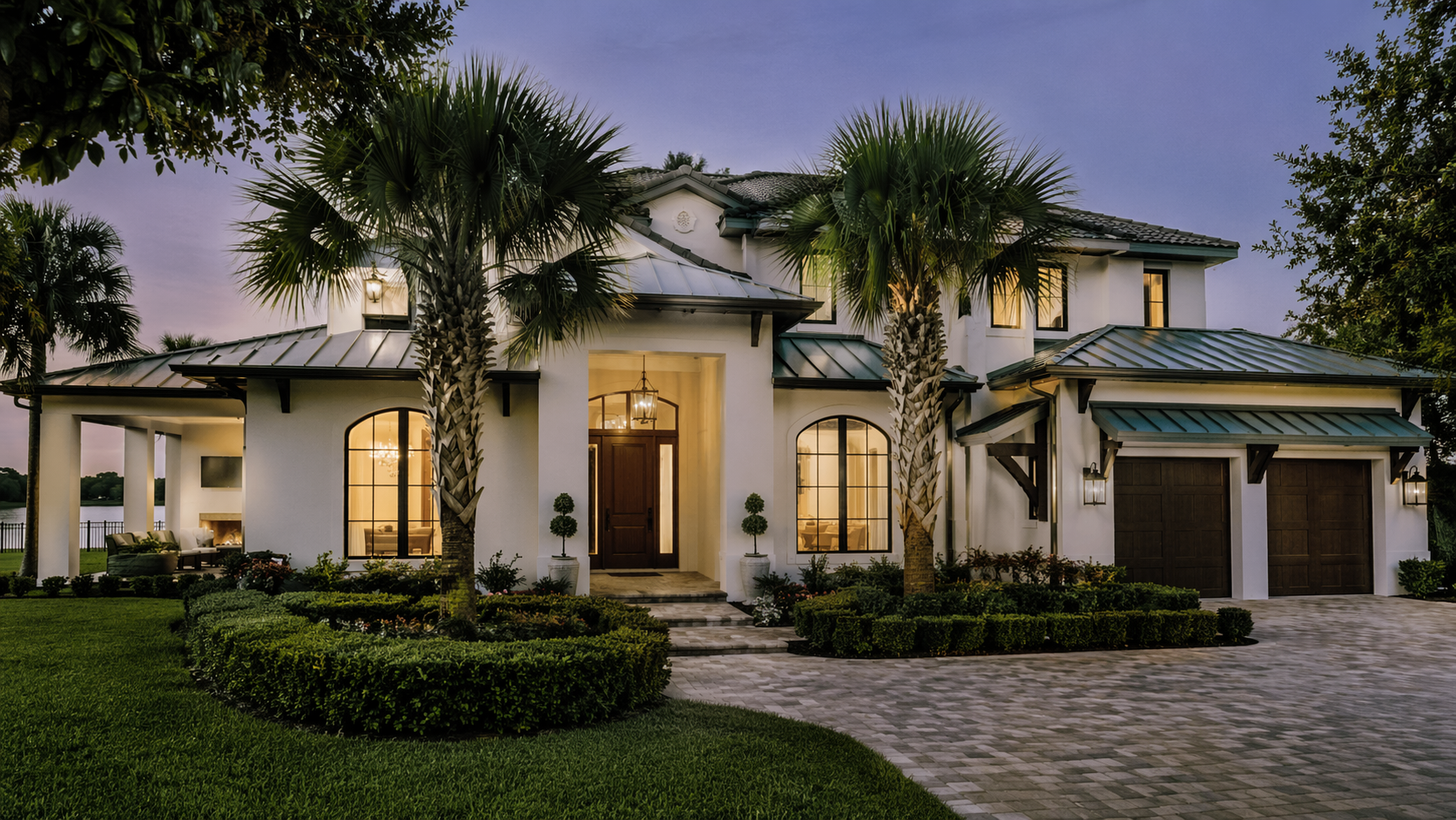 Established luxury custom home in Central Florida at twilight with mature landscaping, a covered lanai, and lakefront views